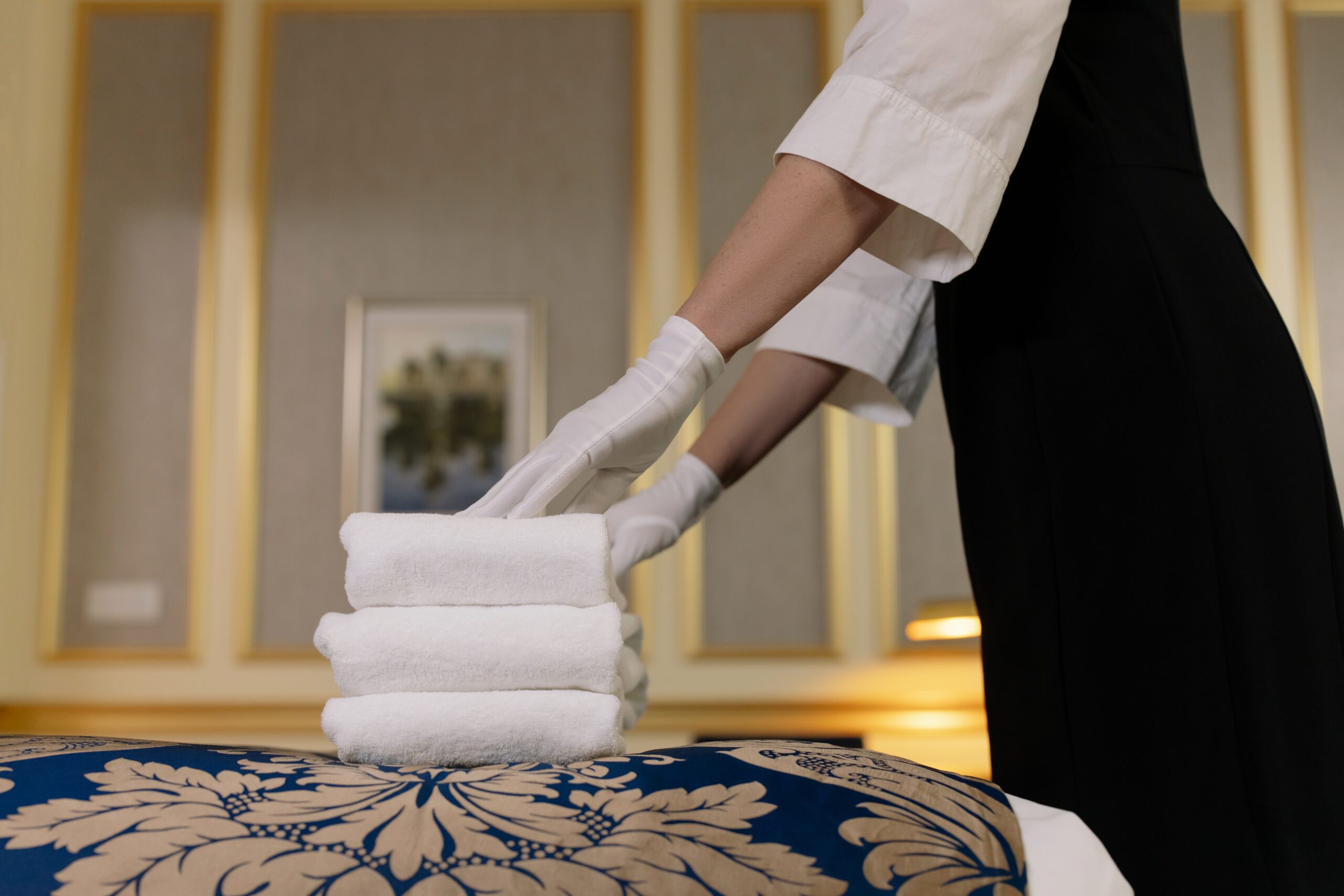 Woman putting a Stack of Towels on a Bed