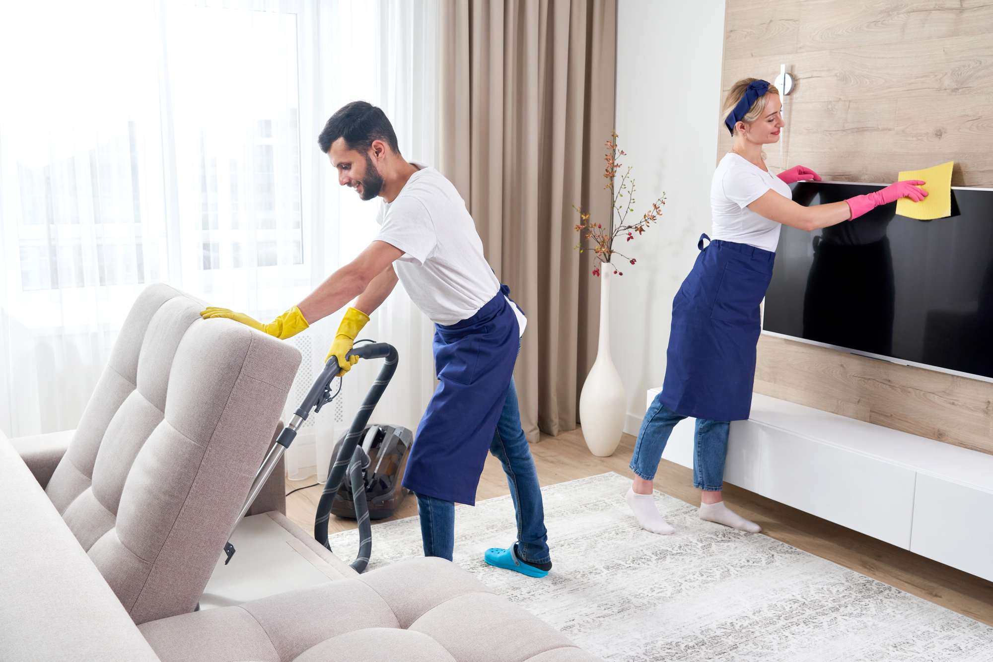 Professional cleaners cleaning living room of a small rental property